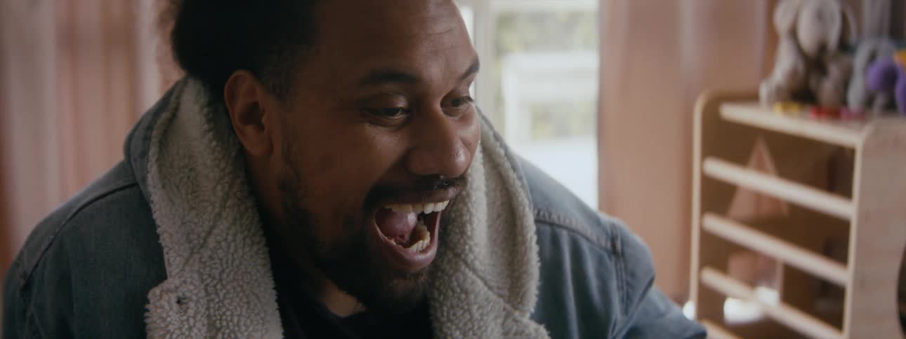 A black man is drinking out of a cup and laughing