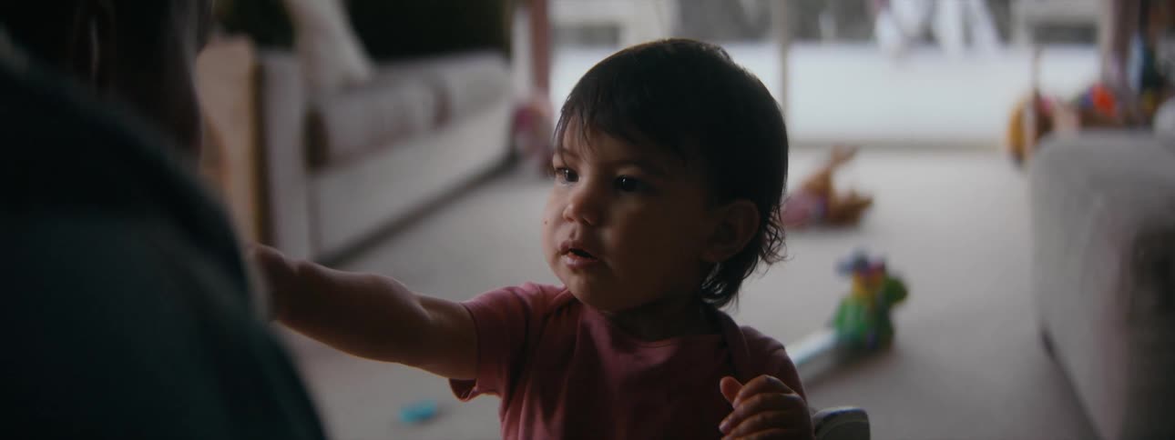 A little girl at home takes a bite of a cracker and then offers her mother a bite