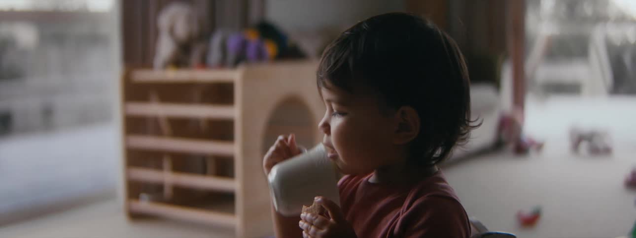 A toddler is sitting down on the floor and playing with a cup