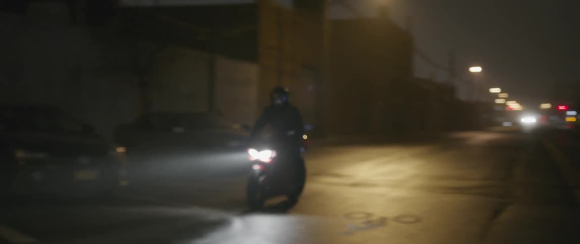Motorcycles are driving down a dark road