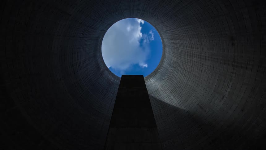 A timelapse shot of clouds and sunlight moving across the round opening at the top of a nuclear cooling tower