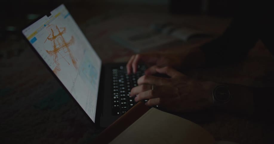 A man working on his laptop while lying down at home at night