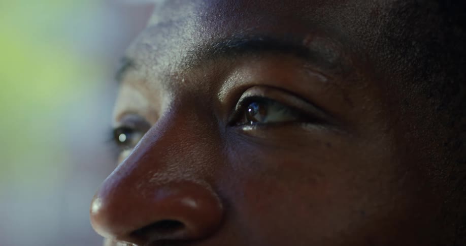 The face of a man deep in thought eyes glistening and reflecting light