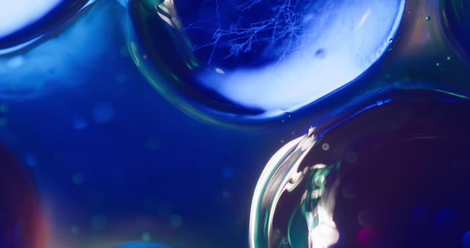 Bubbles reflecting light and blue color shifting on a liquid surface