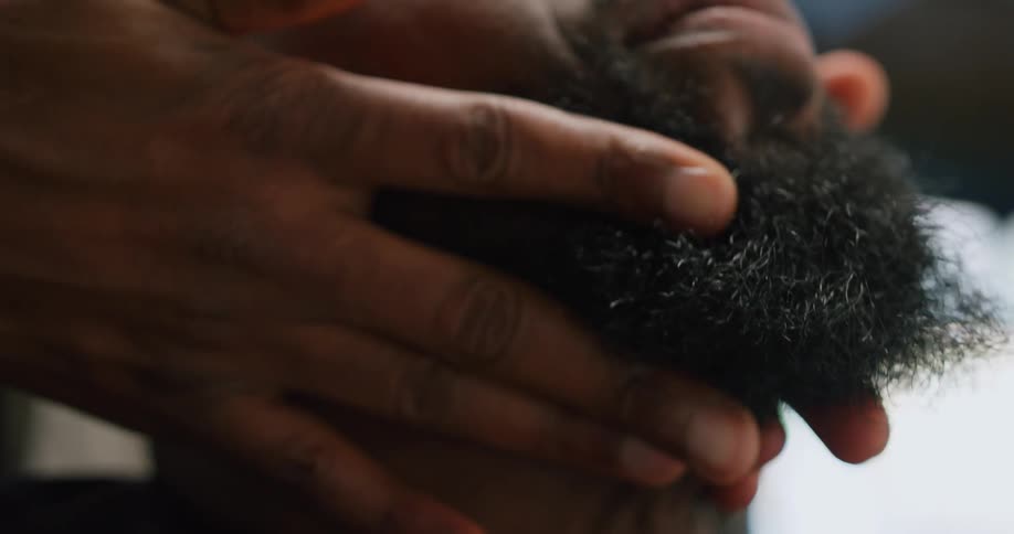 A barber massages a mans chin and beard
