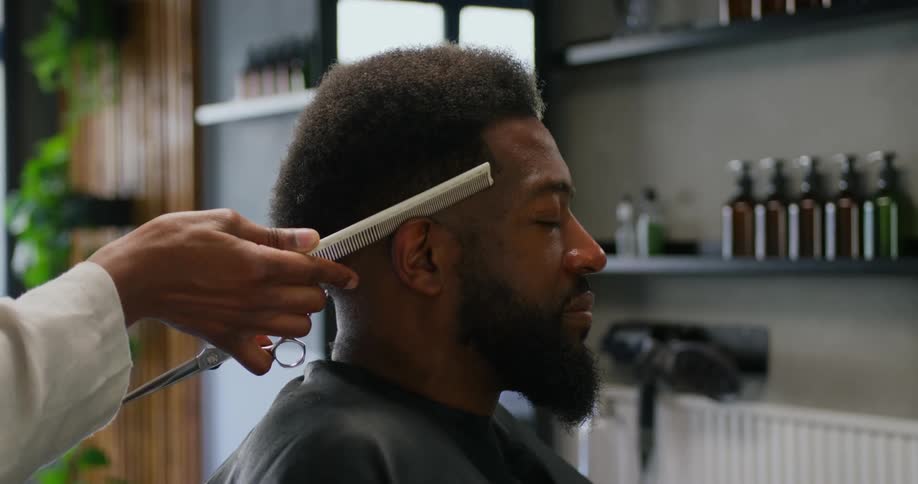 A barber uses a hot comb on a clients edges