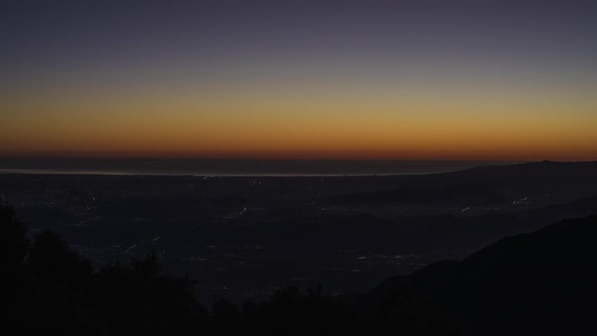 A mountain range glows with the reflection of the sun setting