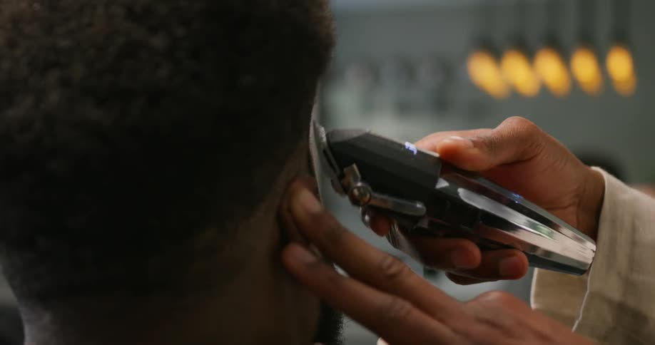 A barber is cutting a mans hair with an electric razor