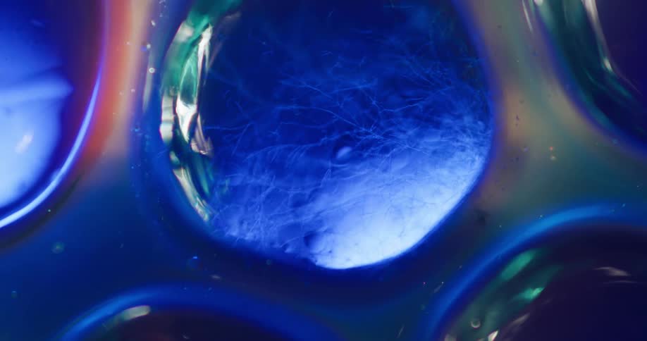 Uneven circles like windows show a light reflecting off of blue fibers