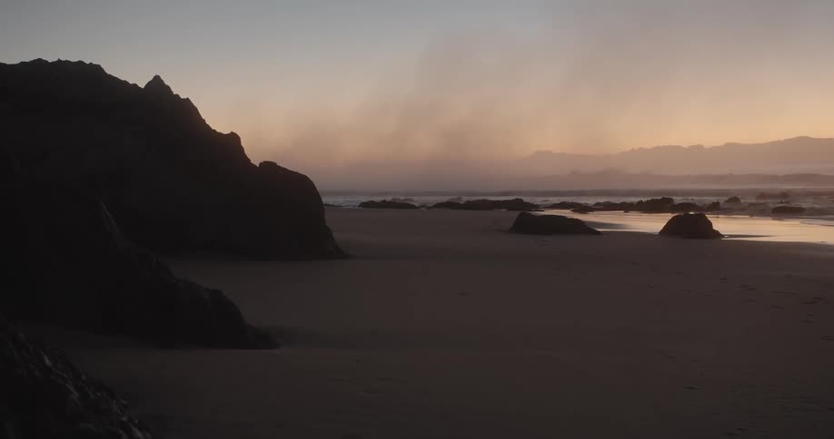 View of beach next to sea at sunset
