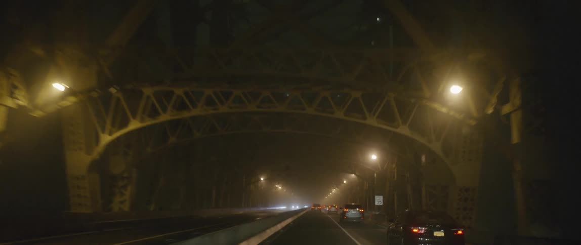 Cars move across a bridge on a foggy night