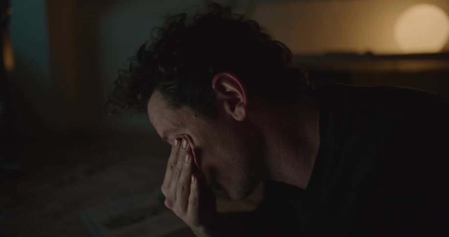 Tired man rubs his eyes using laptop in room at night