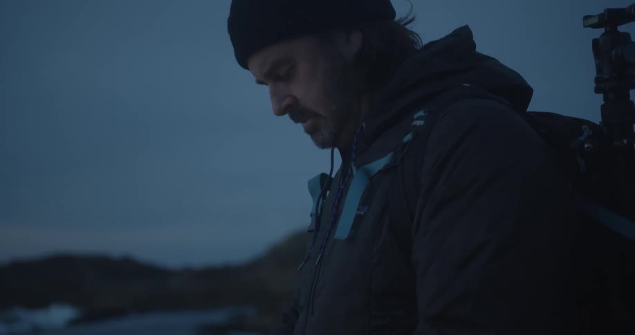 Photographer looking at phone before sunrise on the coast