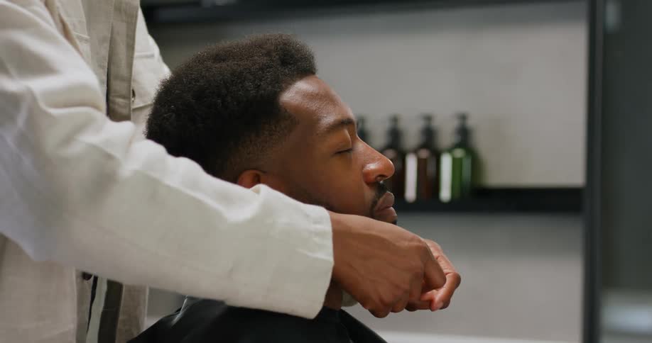 A barber is giving a facial massage to a customer