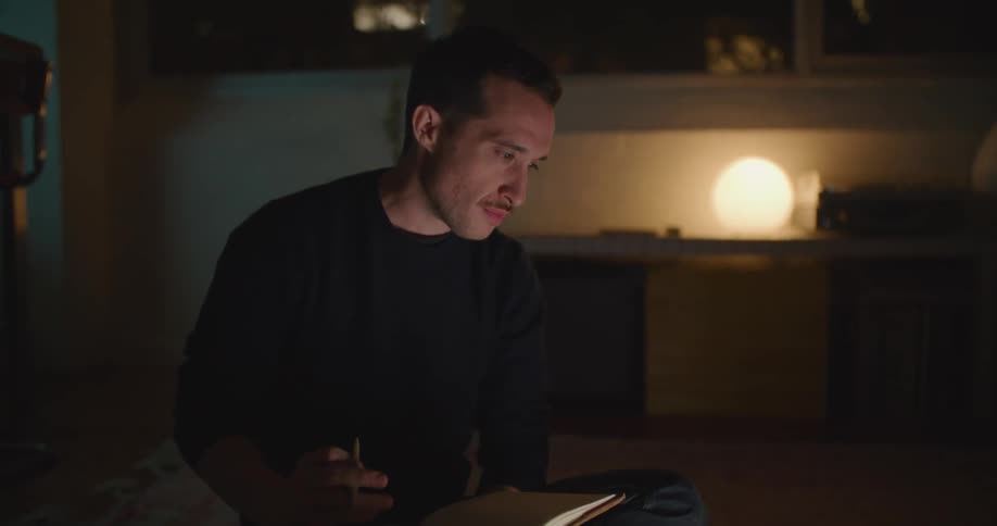 A man takes notes as he looks at his laptop