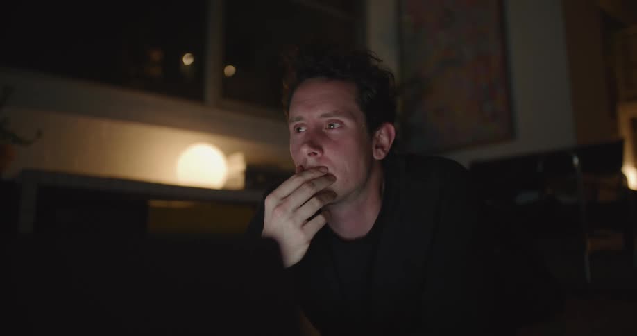 A man rubs his face then smiles and types on a computer