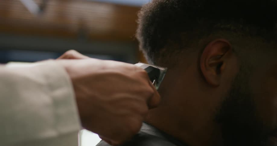 Barber combs and trims hair on clients neck