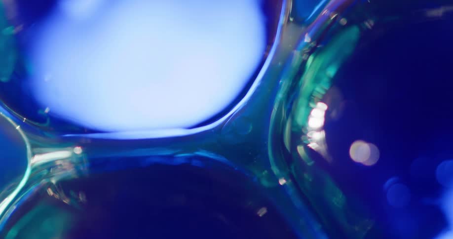 Blue bubbles move in a liquid like substance with a green tint and a light blue glow