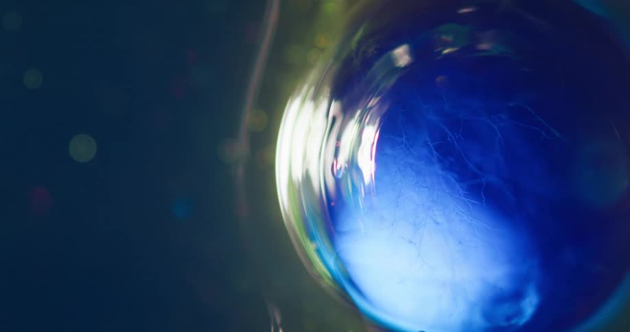A light shines and brightens on the surface of a blue reflective bubble