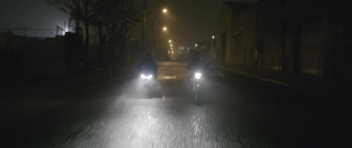 Two people riding motorcycles down a street
