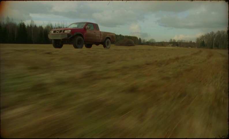A view of a truck driving outdoors on a field