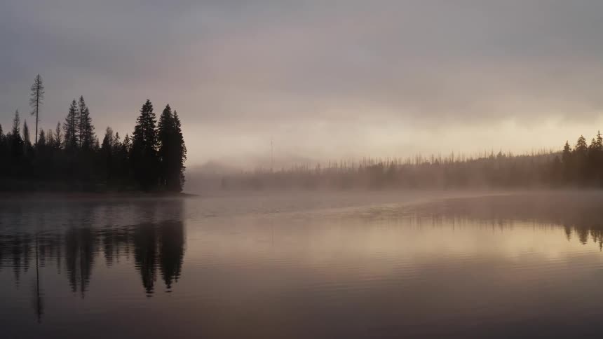 Rain is falling on a lake and forest in the mountains