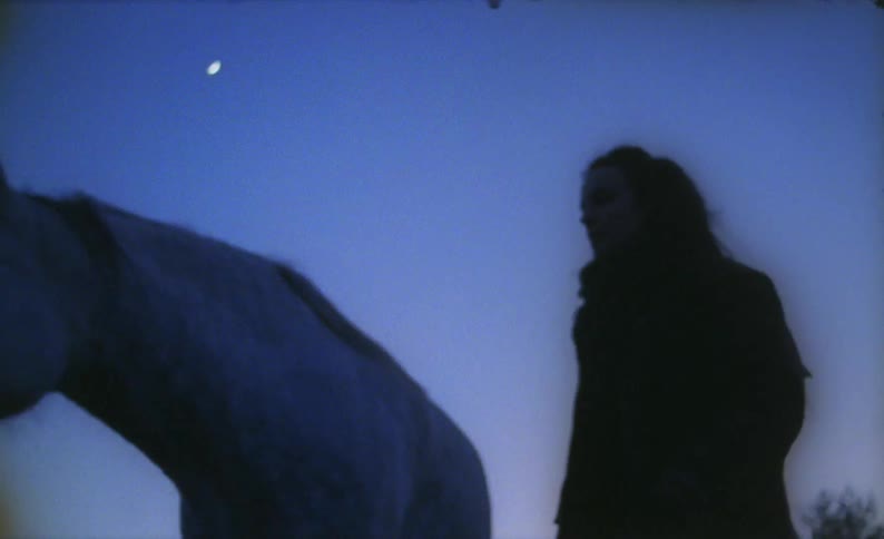 A woman is petting a horse outdoors during the night time