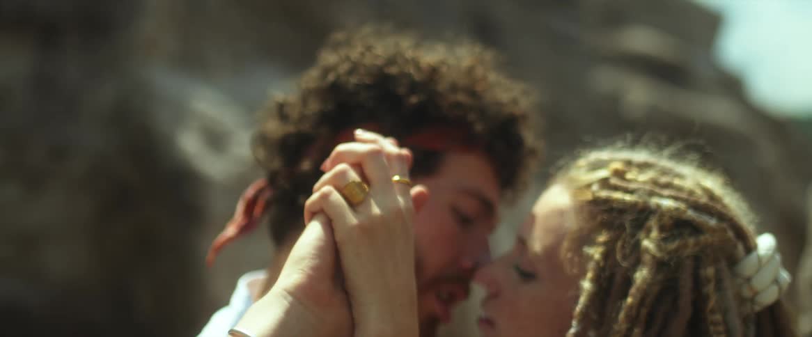 A man and woman are close together and kissing near a mountain