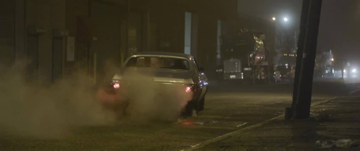 A car speeds off down a street at night