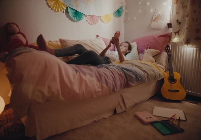 A view of a child using a smartphone in her room