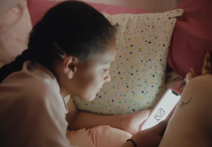A girl lying on her bed holding her phone smiling at the screen