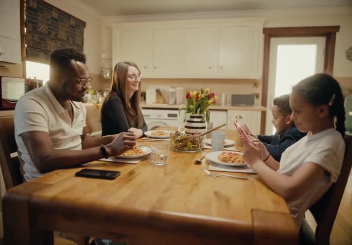Parents watch as children concentrate on smartphones and ignore food