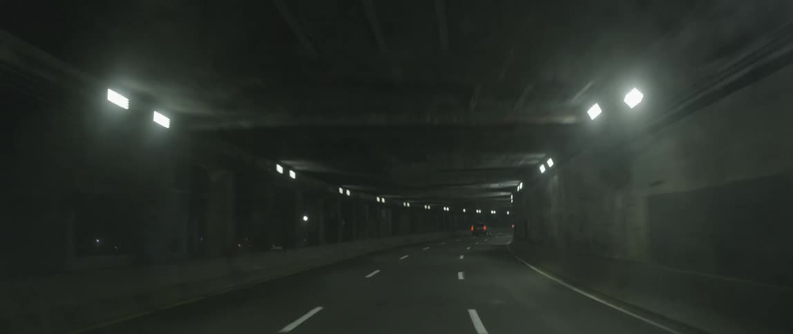 Cars travel down a winding tunnel road