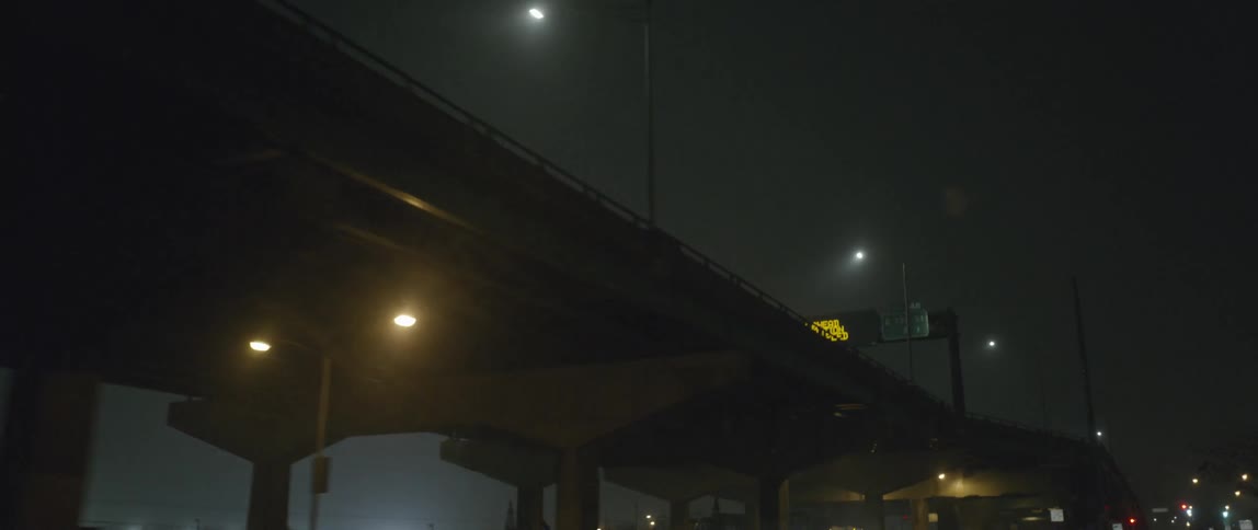 Traffic under a bridge in a city at night