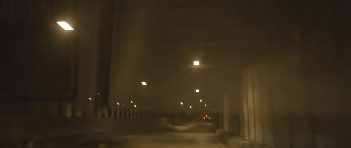 A car drives under a bridge at night