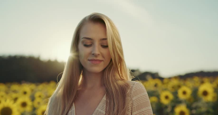 A woman posing with a field of sunflowers behind her