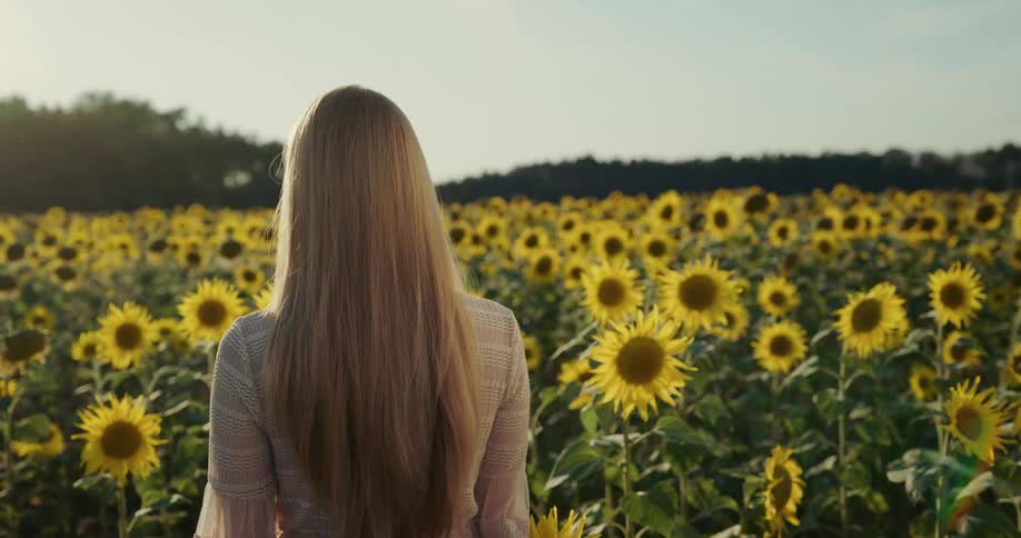 A woman is walking through a field of flowers at dusk