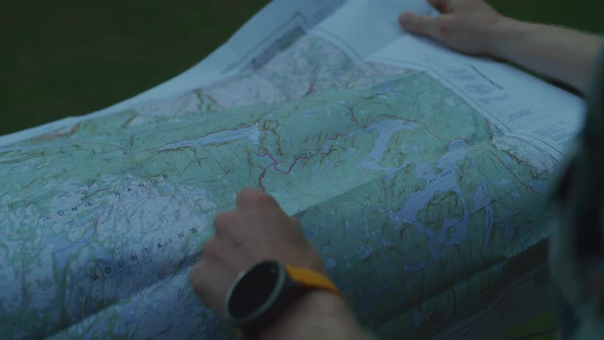 A man is holding a map and pointing to a route marked in red