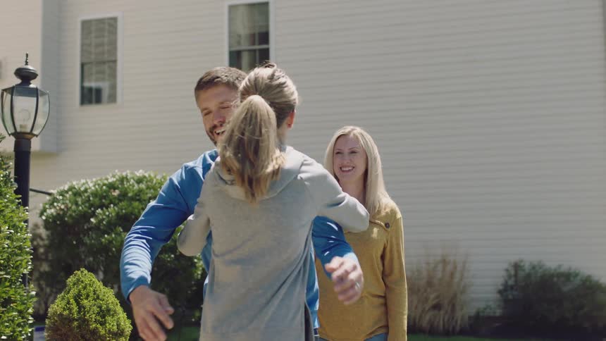 A girl packs her car and hugs her parents