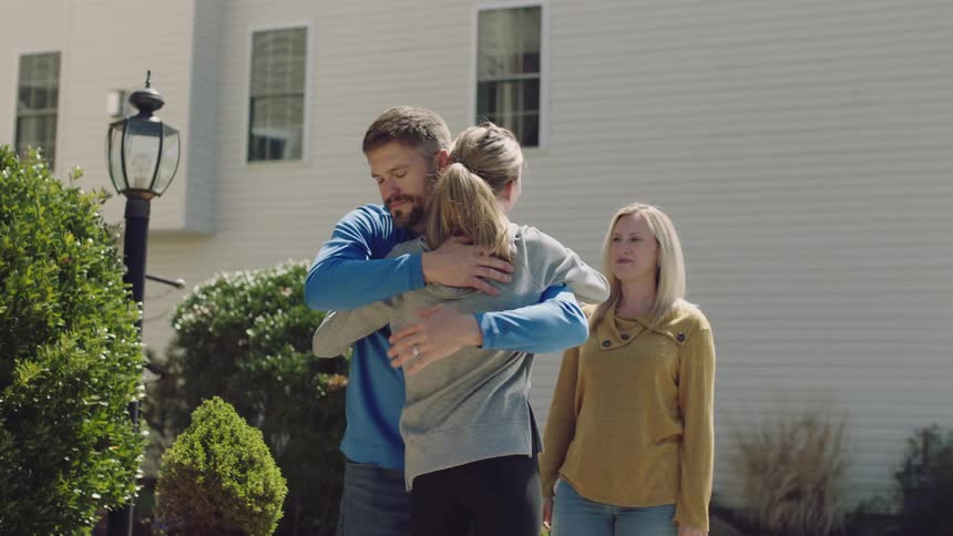 A daughter packs her things in the car and hugs her parents