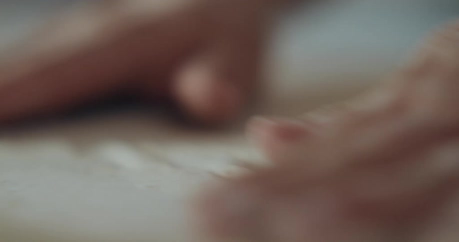 Hands stretch and spin dough on a floured surface