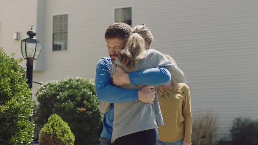 A teenage girl packs her car then gives her parents a hug goodbye
