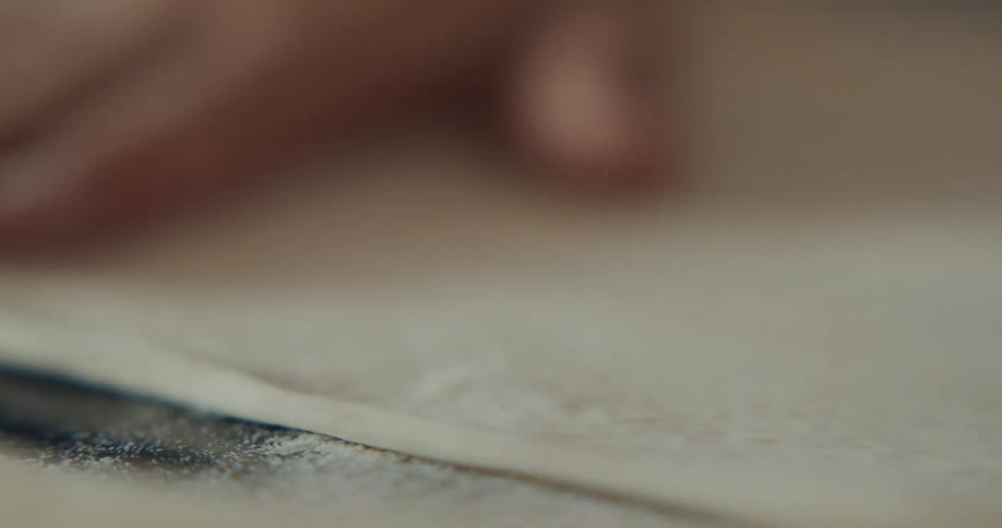 Close up of hands kneading a disk of dough over a metallic surface