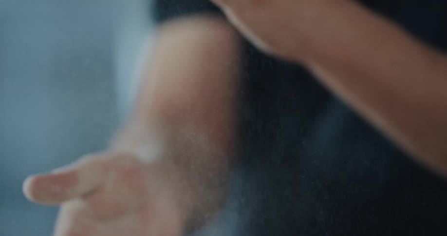 A man is removing flour ingredients off of his hands