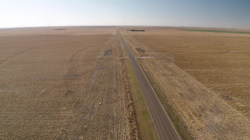 Aerial view of a road through the fields on a farmland at daytime