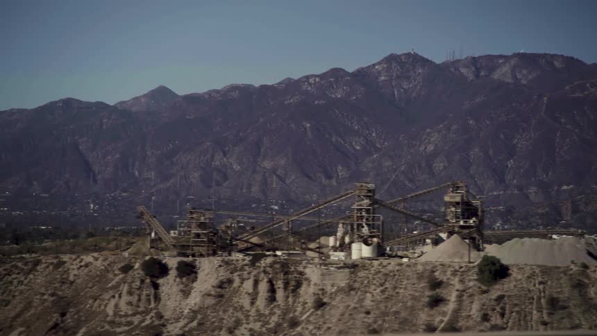 A large mining operation is at the base of a large mountain