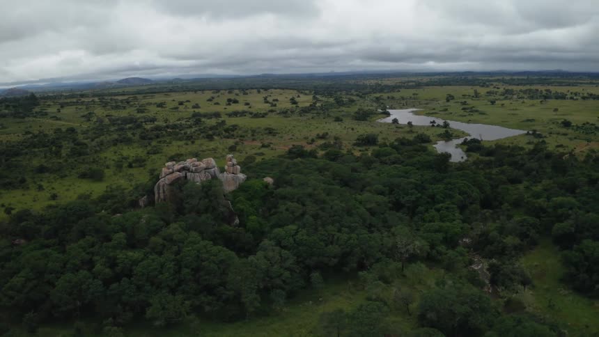 Aerial view of a rock formation surrounded by trees and a river