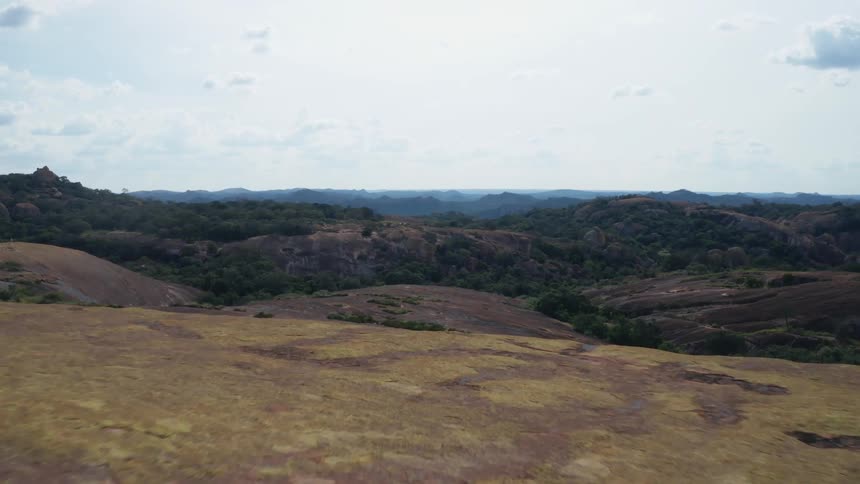 Aerial of a flat rocky mountaintop in a forest