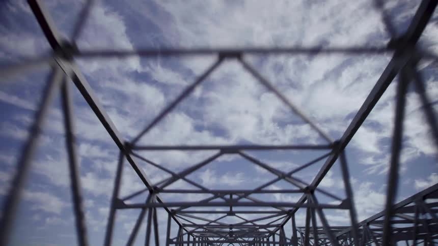 Straight up through a bridge trellis the clouds are spread out and wispy