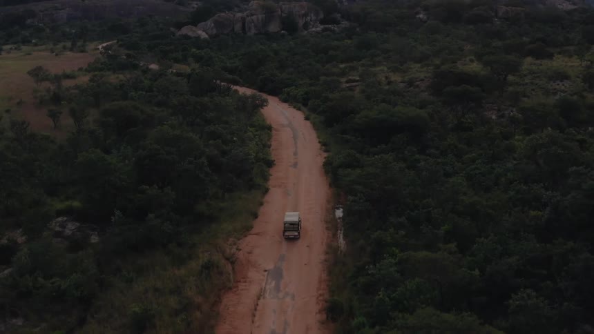 The vehicle is driving on the dirt road